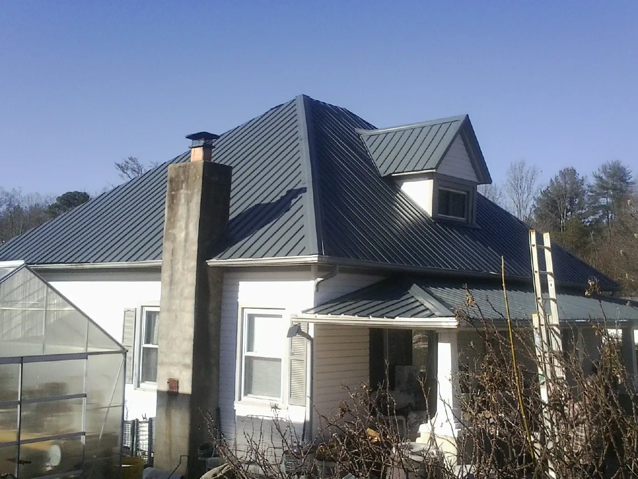 Dark blue standing seam metal roof on a white farmhouse with dormer — Slate & Tile Roof Repair by Roofing Brothers in South Deerfield