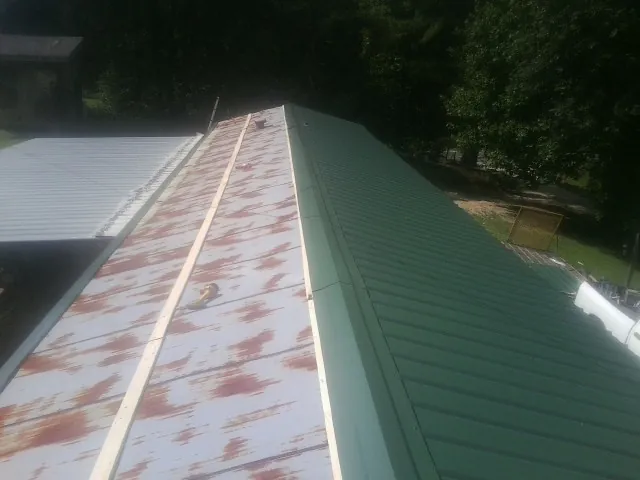Old rusted panels beside newly installed green metal roofing — Wind Damage Roof Repair by Roofing Brothers in South Deerfield