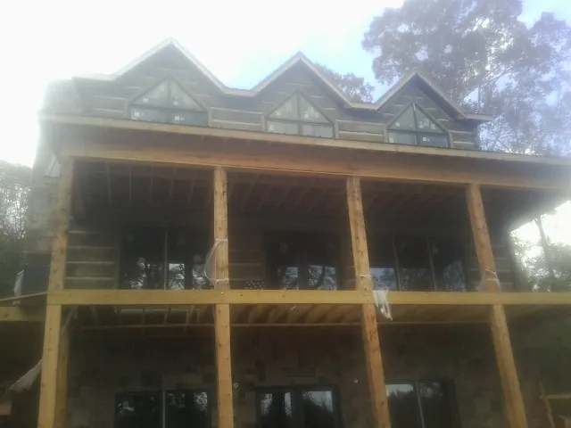 Dormers and porch framing on a large log home under construction — Roof Coating work by our crew in South Deerfield