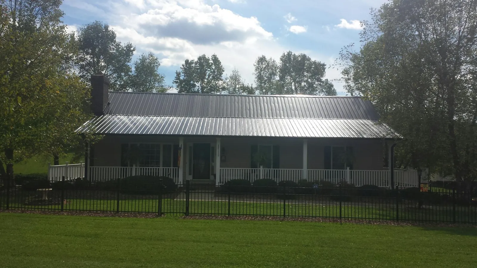 Gray metal roof on a brick ranch with a full width front porch — Gutter Guard Installation work by our crew in South Deerfield