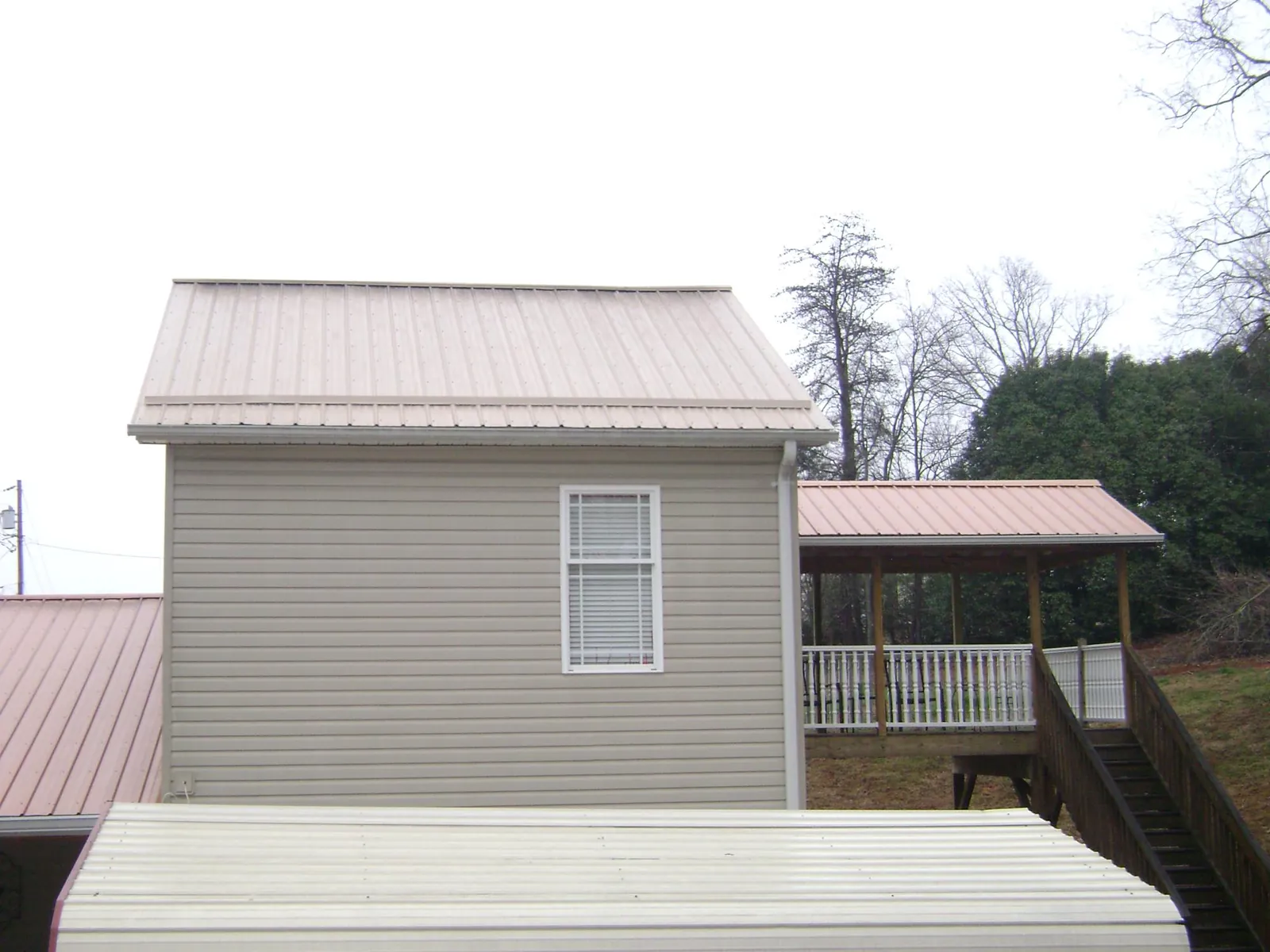 Tan metal roofs on a two story addition and attached porch, from a Roof Replacement job in South Deerfield