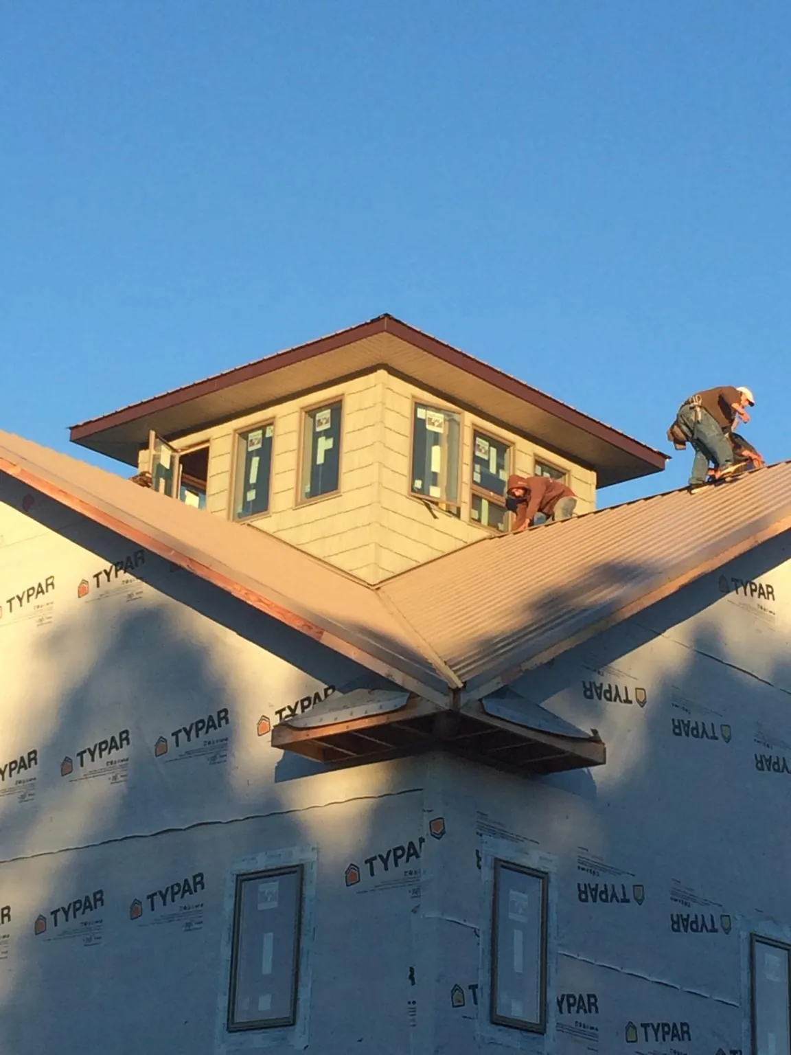 Roofers working around a rooftop cupola on a new metal roof at sunset — Roof Waterproofing in South Deerfield by Roofing Brothers
